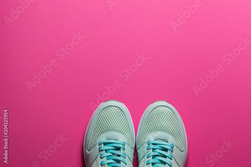 Turquoise sneakers with white soles on a pink background close-up