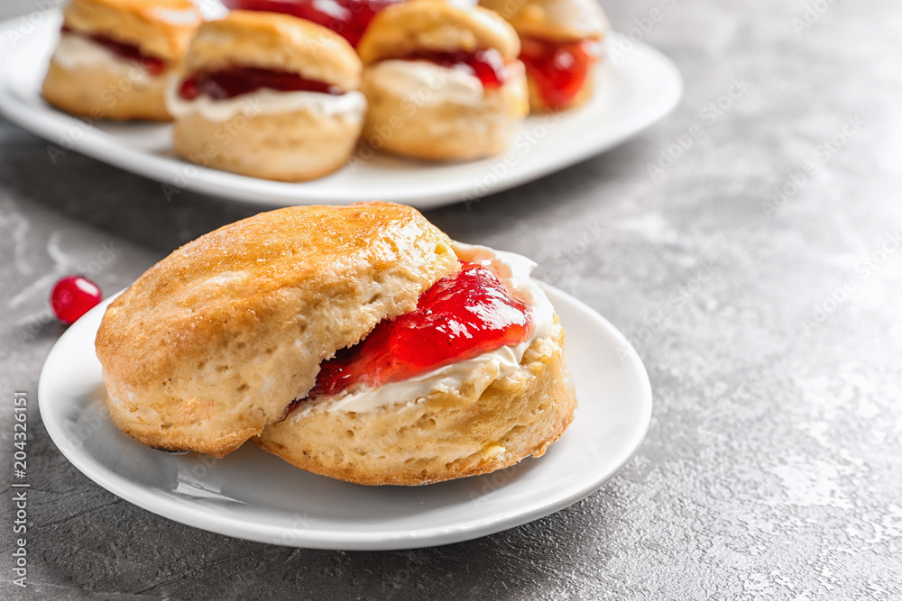 Tasty scone with clotted cream and jam on table, closeup Tasty scone with clotted cream and jam on table, closeup
