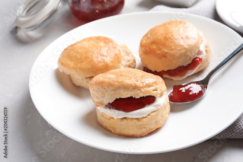 Tasty scones with clotted cream and jam on table