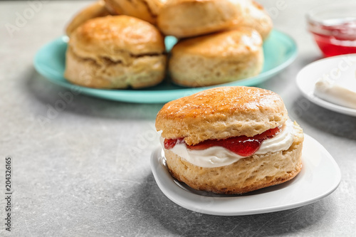 Принти на полотні Tasty scone with clotted cream and jam on plate, closeup