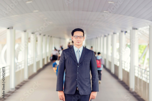 Wallpaper Mural Young Asia handsome businessman with his glasses standing on walkway of modern city. Torontodigital.ca