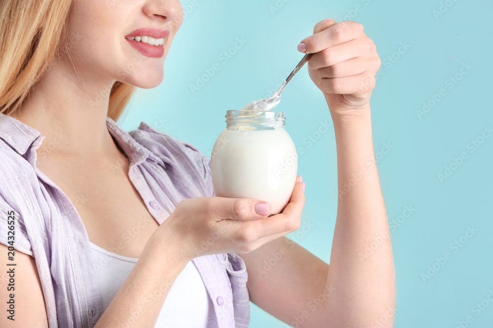 Young woman with yogurt on color background Young woman with yogurt on color background