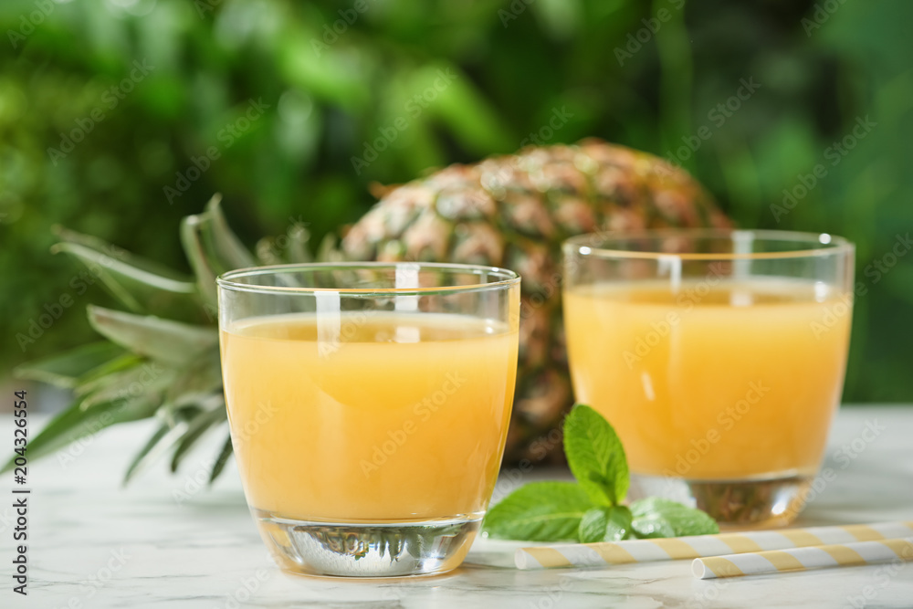 Composition with delicious pineapple juice on table against blurred background Composition with delicious pineapple juice on table against blurred background