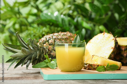 Composition with delicious pineapple juice on table against blurred background