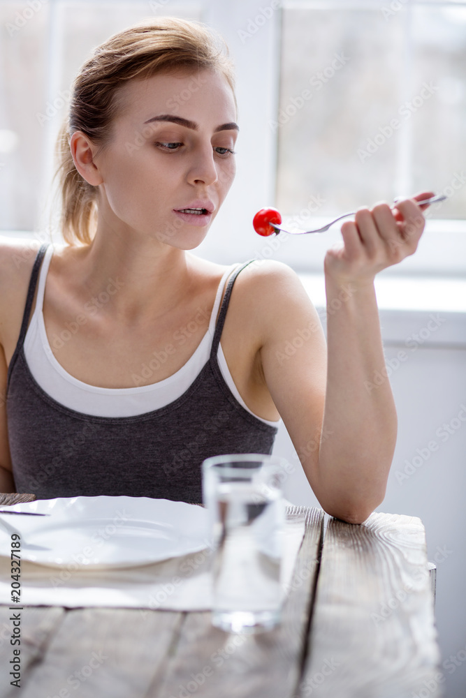 Fresh vegetable. Sad pale woman looking at the tomato while having breakfast Fresh vegetable. Sad pale woman looking at the tomato while having breakfast