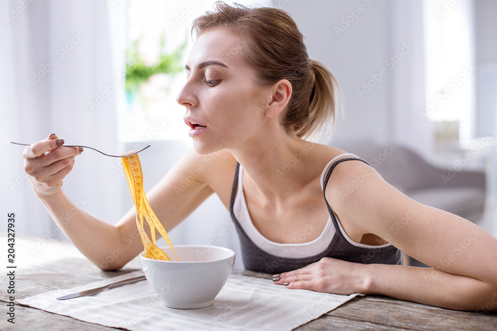 Weight problem. Cheerless underweight woman thinking about her diet while suffering from anorexia Weight problem. Cheerless underweight woman thinking about her diet while suffering from anorexia