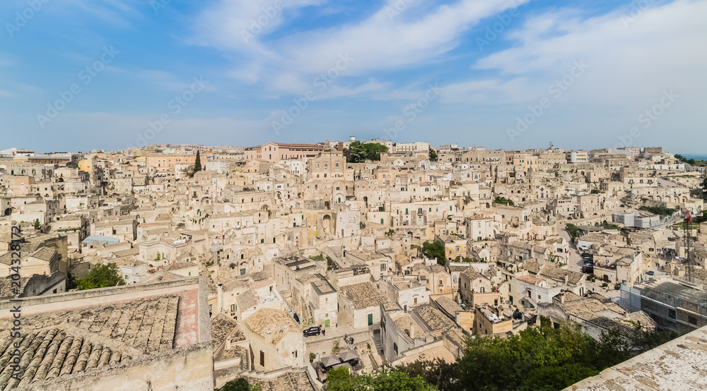 panoramic view of typical stones Sassi di Matera and church of Matera under blue sky with clouds