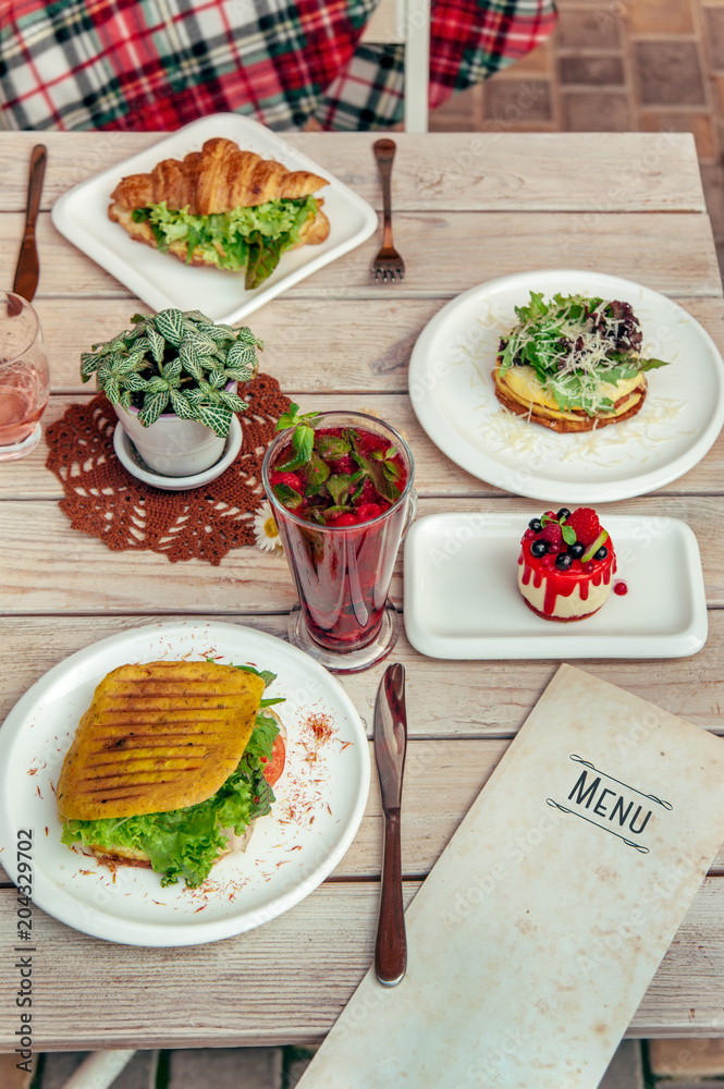 breakfast served cafe table with cheese pancakes, sandwich, croissant and drinks. Top view breakfast served cafe table with cheese pancakes, sandwich, croissant and drinks. Top view