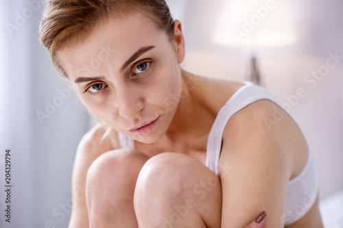 Anorexia victim. Sad underweight woman sitting on the bed while suffering from anorexia photo