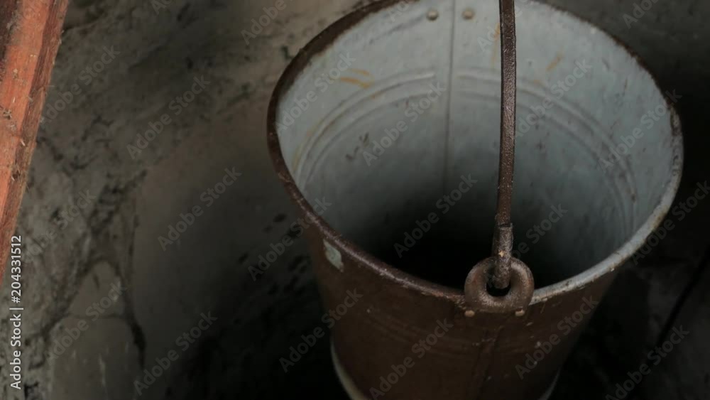 empty metal bucket hanging in a rural well empty metal bucket hanging in a rural well