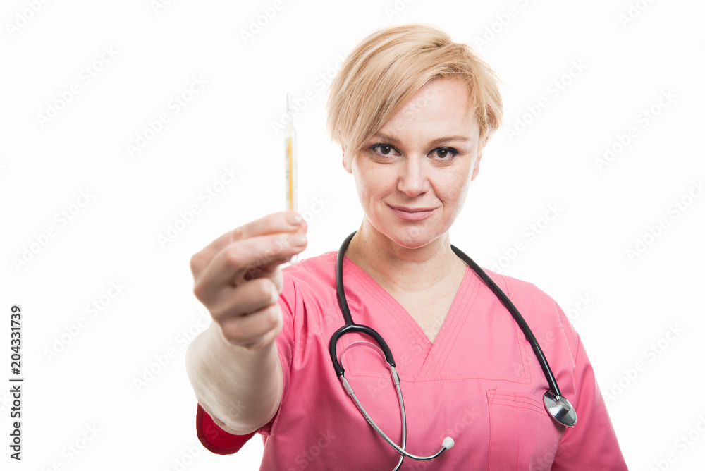 Attractive female nurse wearing pink scrubs showing thermometer
