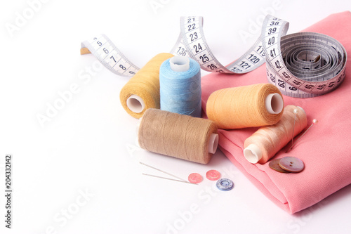 Sewing accessories and fabric on a white background. Sewing threads, needles, pins, fabric, buttons and sewing centimeter. © White bear studio 