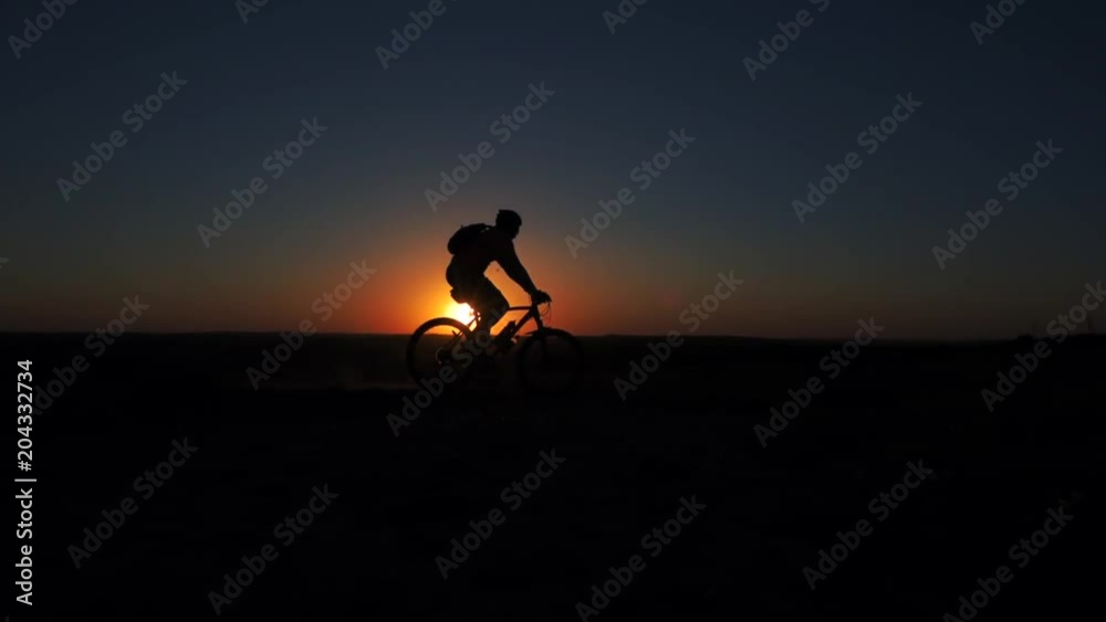 A young man is actively spending time on his bike at sunset. A bike ride in the sunset A young man is actively spending time on his bike at sunset. A bike ride in the sunset