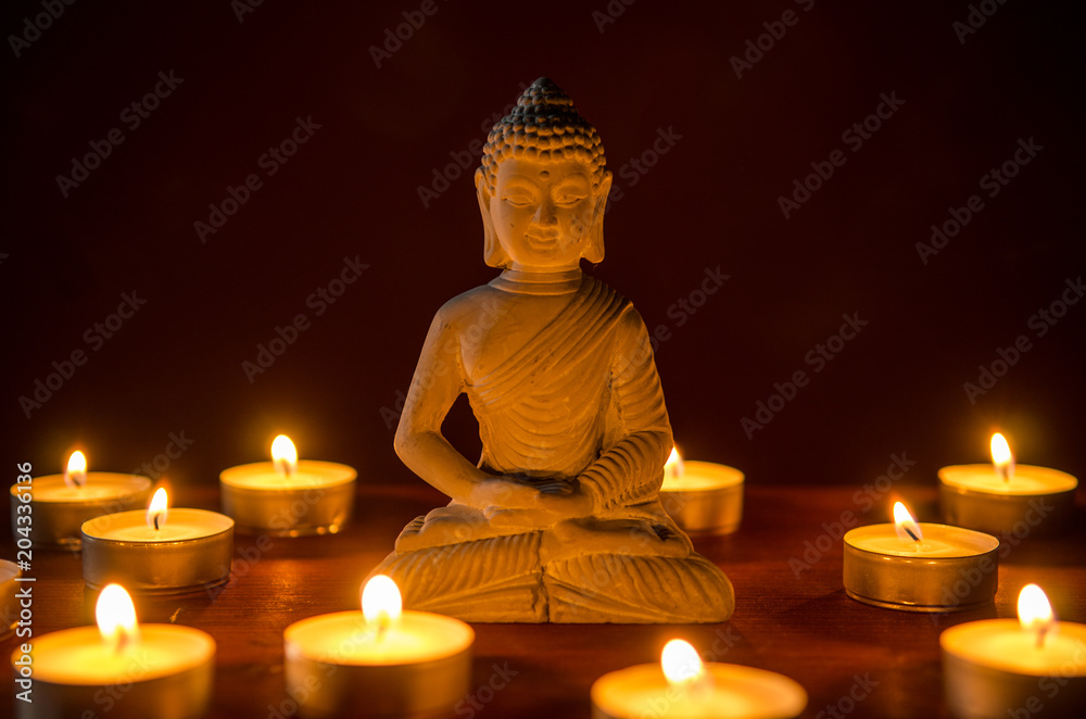little buddha statue surrounded by tea candles