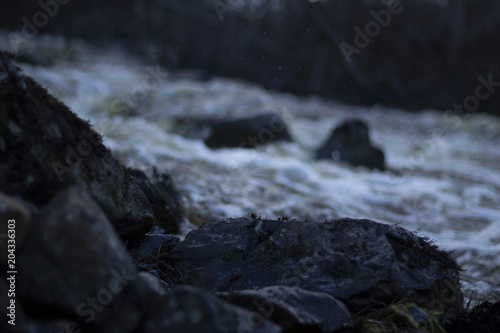 Wet stones in the foreground, spring flood of a usually small river in a forest in northern Sweden. © Niklas NW