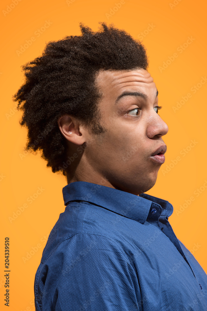Obraz premium The young attractive man looking suprised isolated on orange