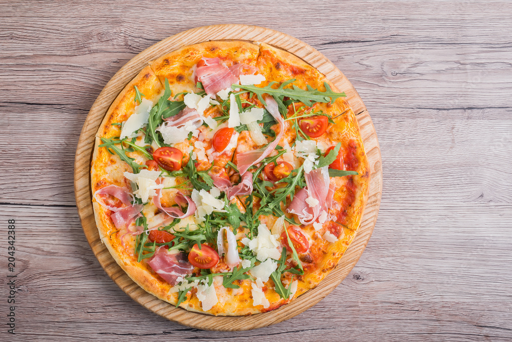 Fresh pizza with prosciutto meat, tomato and green arugula Fresh pizza with prosciutto meat, tomato and green arugula