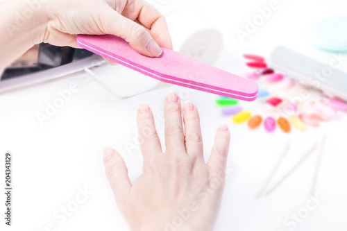 Woman doing manicure with pink file on white table