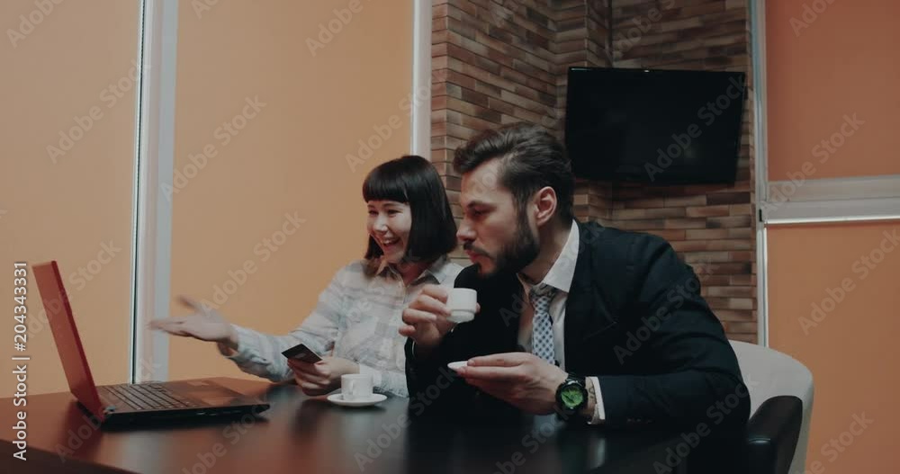 Two office workers at break time in the cafe order something using a credit card they are the enthusiastic Two office workers at break time in the cafe order something using a credit card they are the enthusiastic