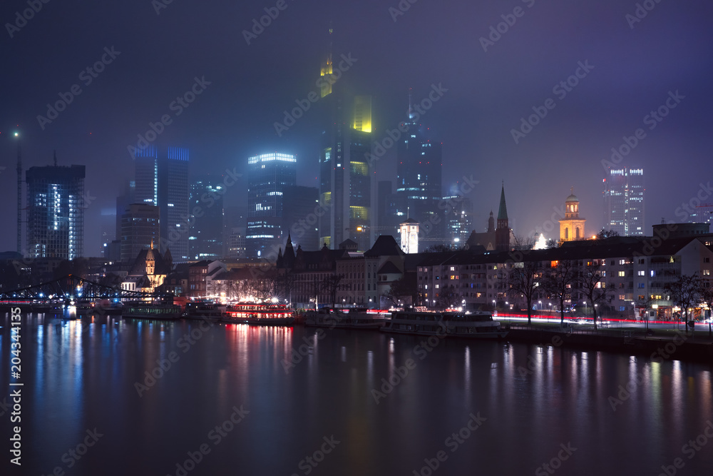 Picturesque view of business district with skyscrapers and Old Town with mirror reflections in the river during foggy morning blue hour, Frankfurt am Main, Germany