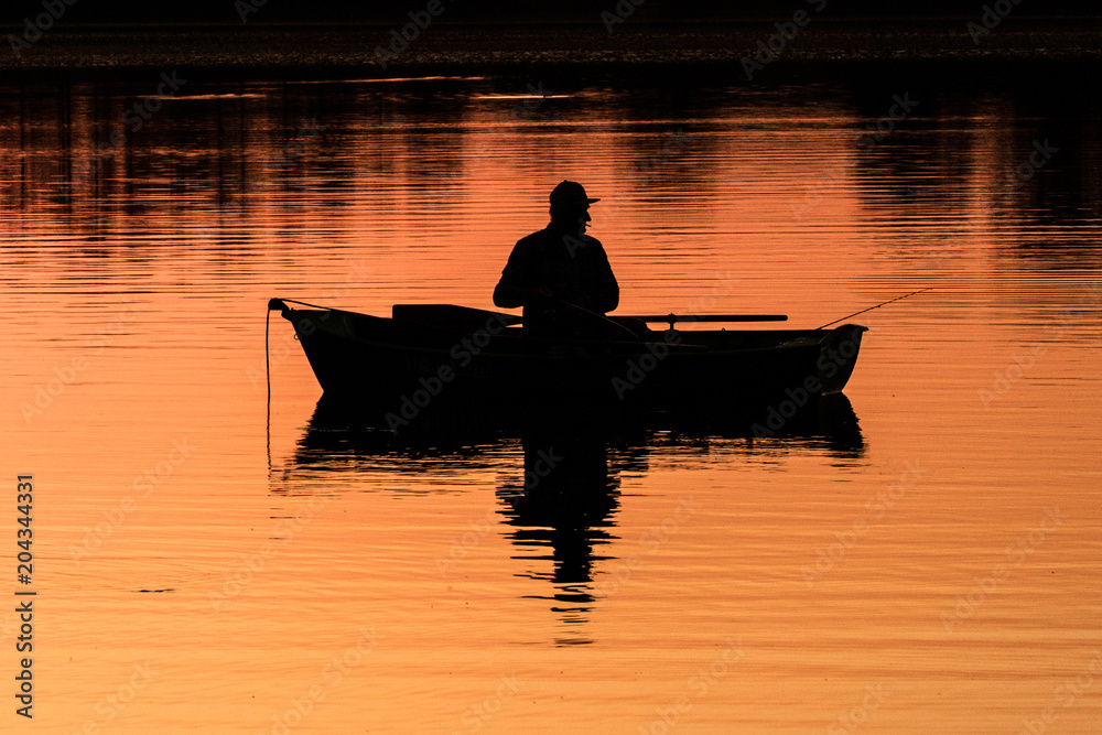 view of the lake with an angler on the boat at sunset