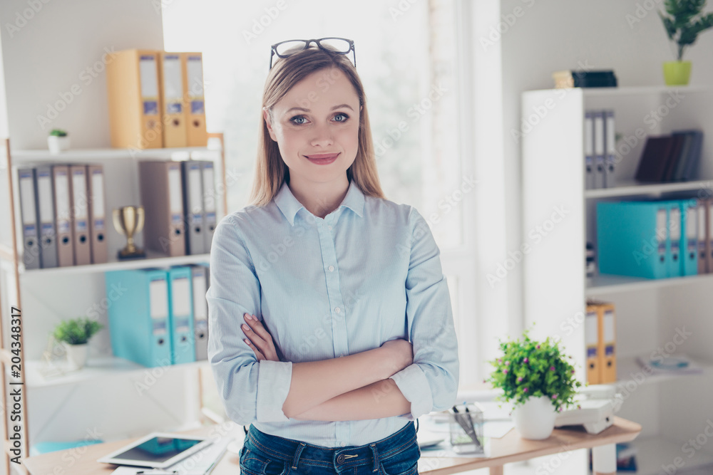Portrait of nice, cute, positive woman having her arms crossed looking at camera standing in workplace, workstation Portrait of nice, cute, positive woman having her arms crossed looking at camera standing in workplace, workstation