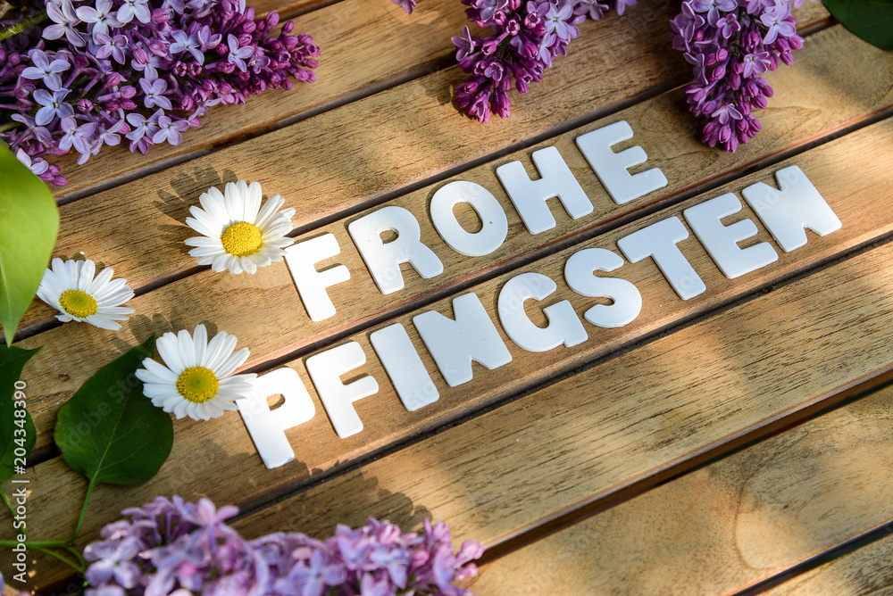 Frohe Pfingsten Wörter auf einem Holtbrett mit Flieder Blumenst - obrazy, fototapety, plakaty 