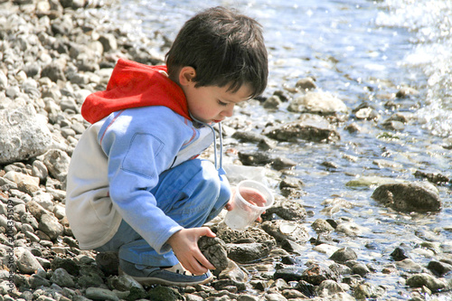 Little boy playing with pebbles at the beach