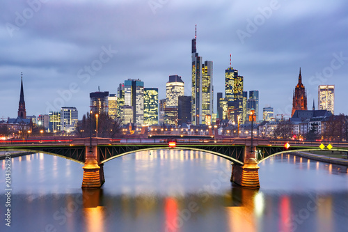 Picturesque view of Frankfurt am Main skyline and Ignatz Bubis Brucke bridge during evening blue hour with mirror reflections in the river  Germany