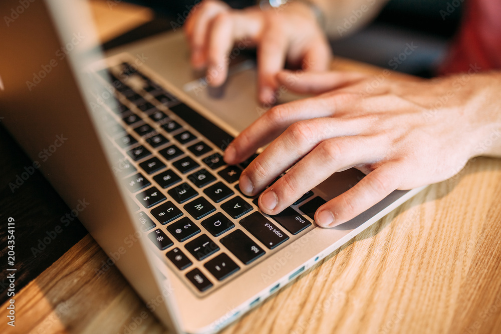 Hands close up of fingers typing on laptop, a man in a cafe Hands close up of fingers typing on laptop, a man in a cafe