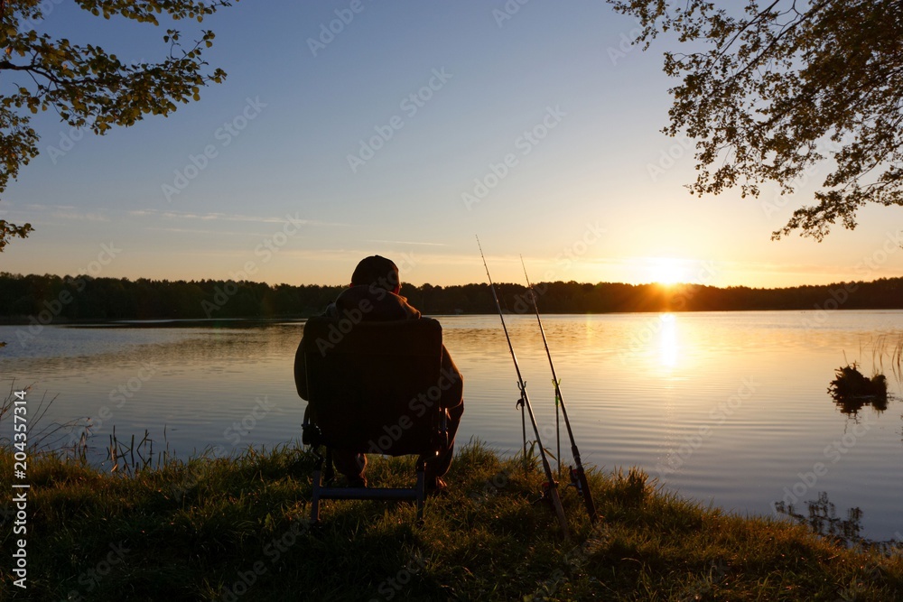 Fisherman sitting on the chair and fishing on the shore of lake during sunrise
Fisherman sitting on the chair and fishing on the shore of lake during sunrise
