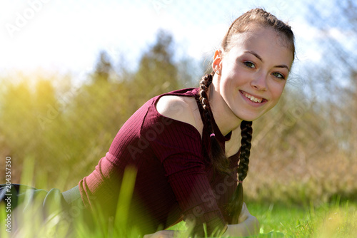 Smiling caucasian teenager girl liyng in grass on garden. photo