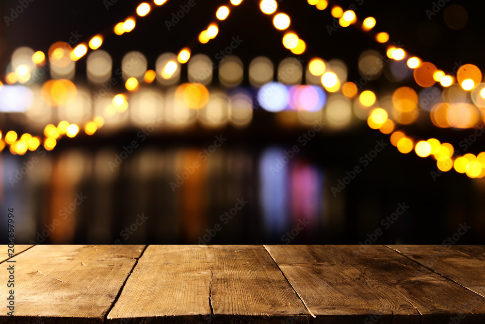 Image of wooden table in front of abstract blurred restaurant lights background. Image of wooden table in front of abstract blurred restaurant lights background.