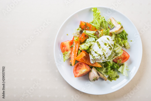 Fresh salad with poached egg, meat, tomato