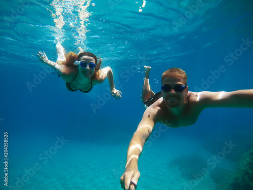 Cheerful couple having fun underwater and making selfie.