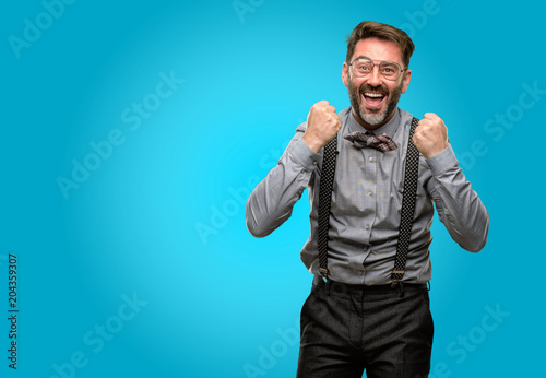 Middle age man, with beard and bow tie happy and excited expressing winning gesture. Successful and celebrating victory, triumphant