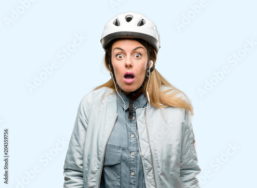 Young woman with bike helmet and earphones scared in shock, expressing panic and fear © Krakenimages.com