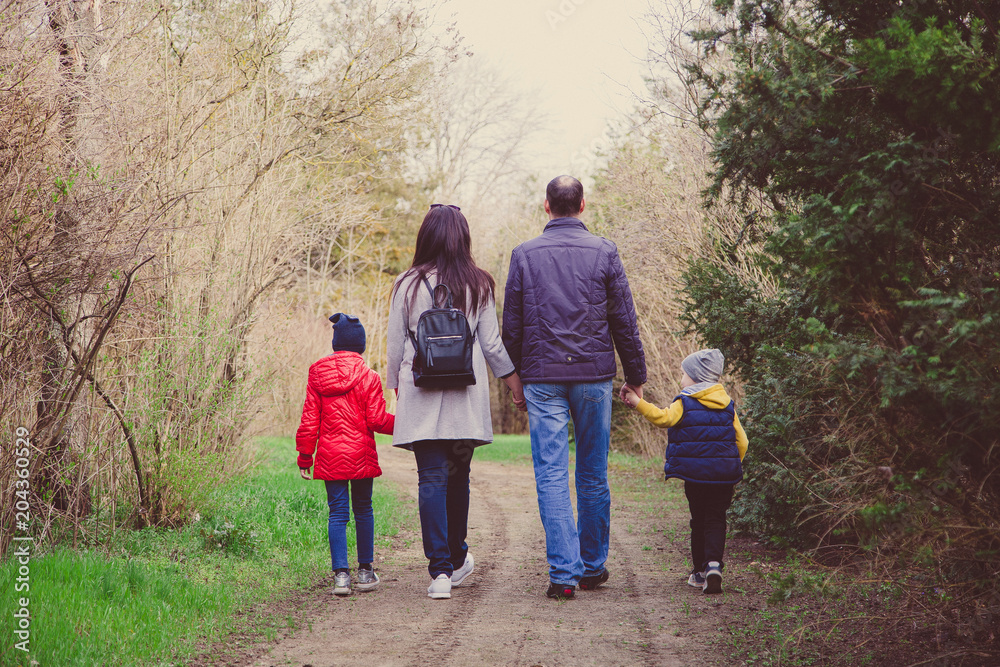 Happy young family spending time together outside in nature. parents holds the hands of a small children Happy young family spending time together outside in nature. parents holds the hands of a small children