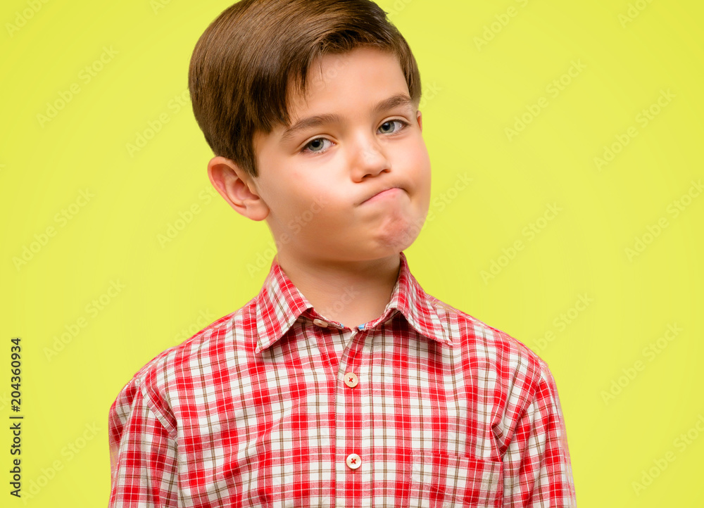 Handsome toddler child with green eyes making funny face fooling over yellow background Handsome toddler child with green eyes making funny face fooling over yellow background