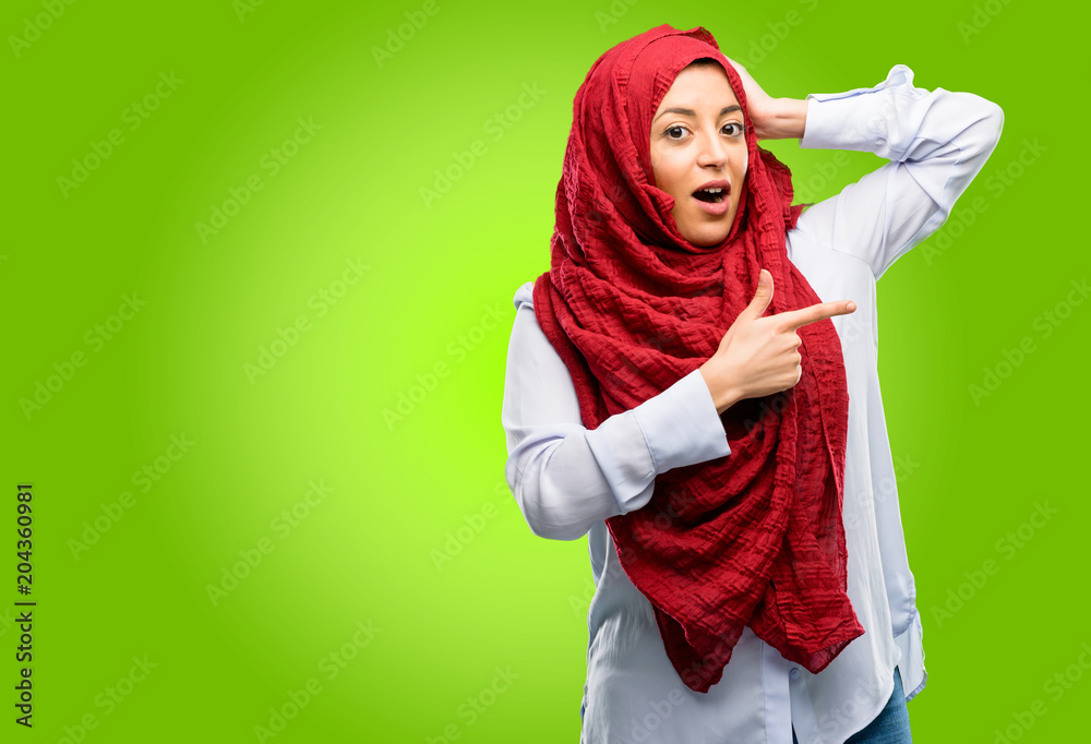 Young arab woman wearing hijab pointing away side with his finger Young arab woman wearing hijab pointing away side with his finger