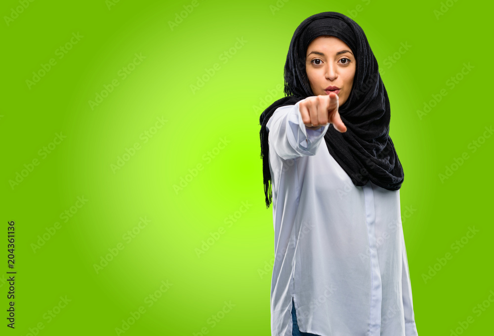 Young arab woman wearing hijab pointing to the front with finger Young arab woman wearing hijab pointing to the front with finger