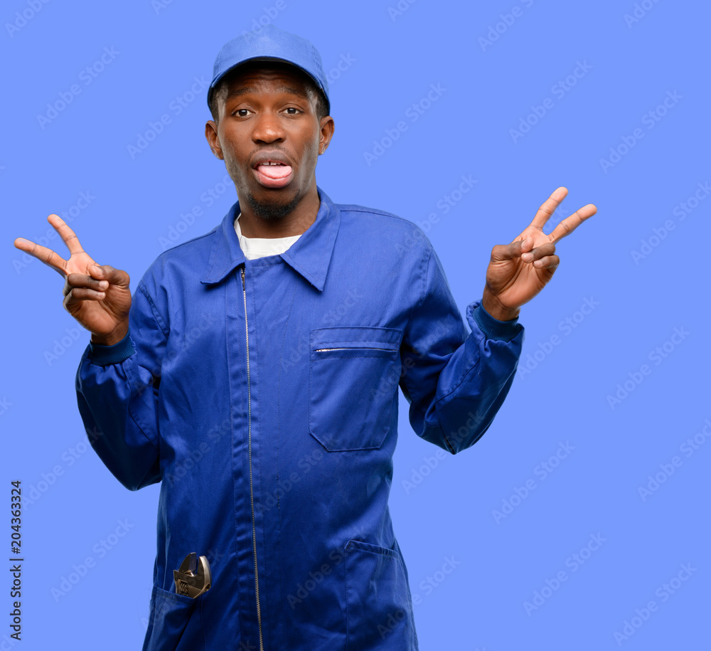 African black plumber man looking at camera showing tong and making victory sign with fingers