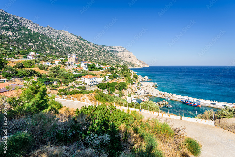 Ikaria Island, Magganitis, Sporades, Greece: Beautiful sunny greek village town orthodox greek church and harbor view to the blue sea with crystal clear water and fishing boats cruising yacht at shore