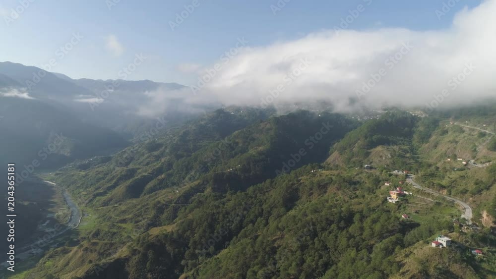 Aerial view of mountains covered forest, trees in clouds and fog. Cordillera region. Luzon, Philippines. Slopes of mountains with evergreen vegetation. Mountainous tropical landscape.