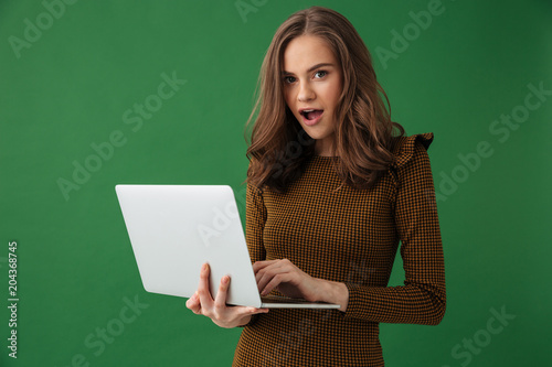 Young emotional woman holding laptop computer looking camera.