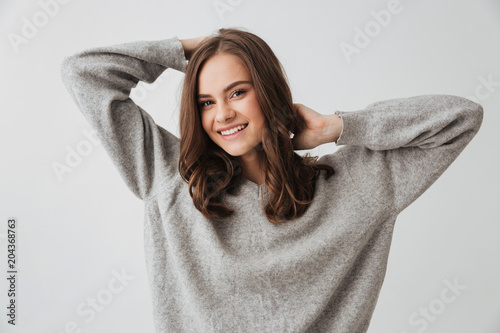 Happy brunette woman in sweater posing and looking at camera