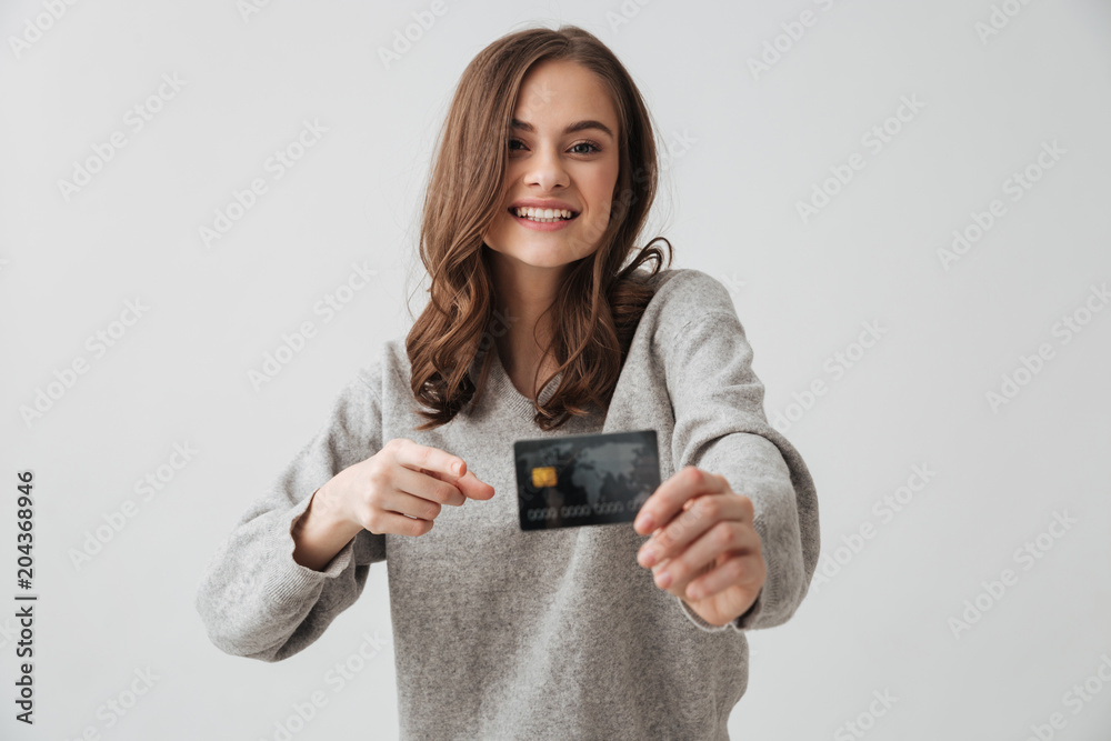 Smiling brunette woman in sweater showing credit card Smiling brunette woman in sweater showing credit card