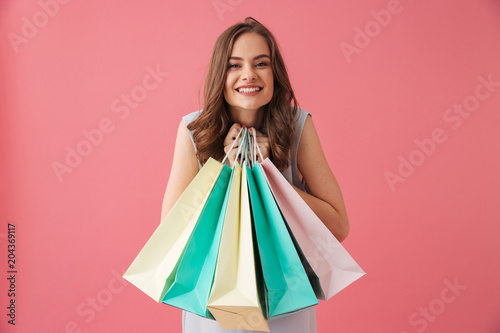 Cheerful young woman holding shopping bags.