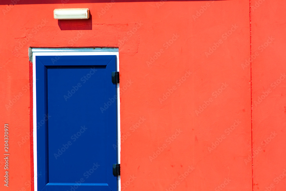 Vibrant colorful paint. Blue painted door on red building.