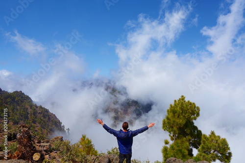 Young man on the top of a volcano which is a part of a hiking trail GR131 Ruta de los Volcanes leading from Fuencaliente to Tazacorte on La Palma, Canary Islands, Spain